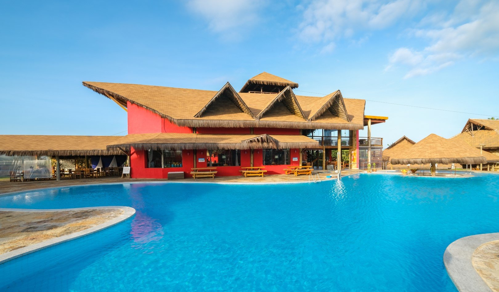 Uma grande piscina com um prédio vermelho ao fundo.