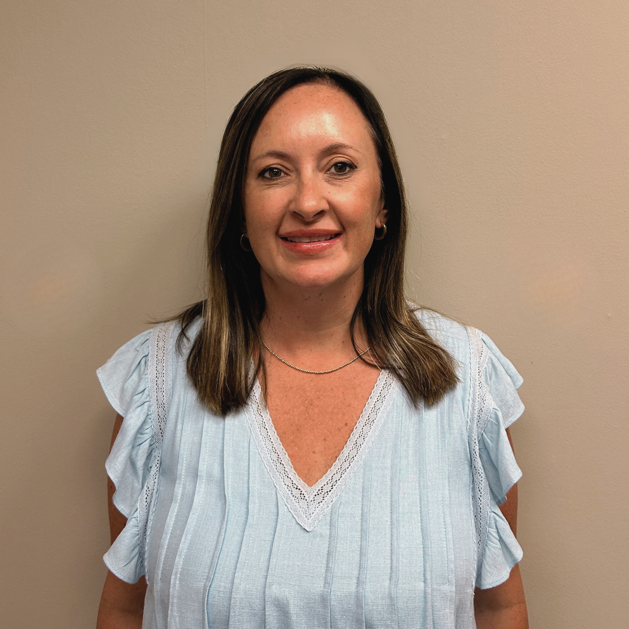 A woman in a pink shirt is smiling for the camera