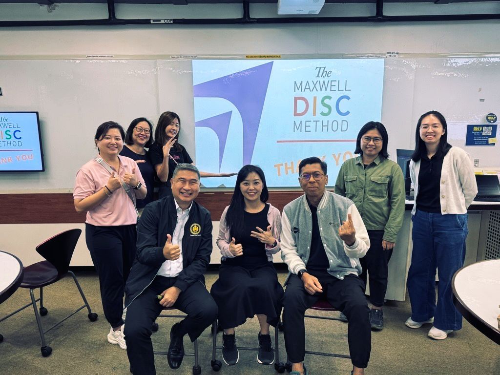 Group of people posing in front of a “DISC” presentation screen in a conference room.
