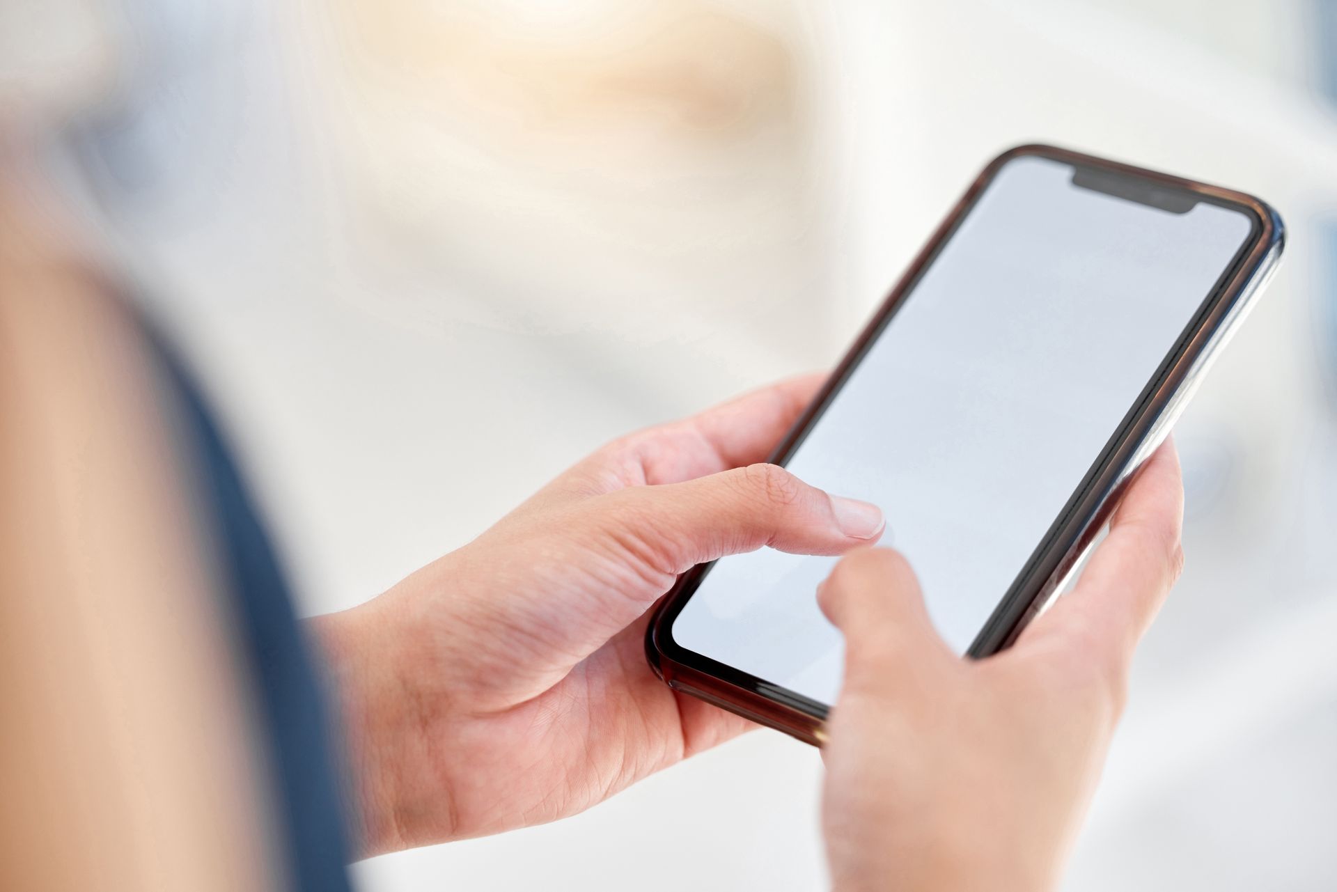 Hands holding a smartphone with a blank screen; tapping the display.