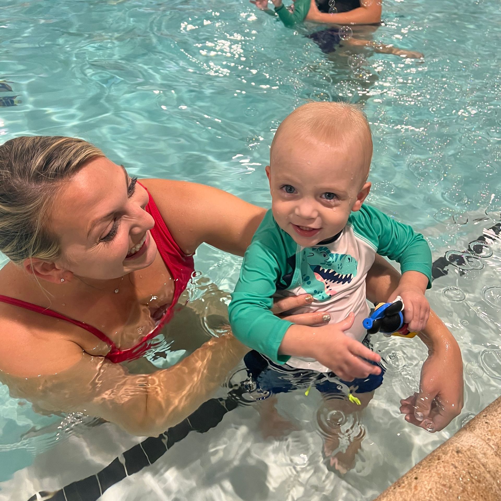 A woman is holding a baby in a swimming pool.