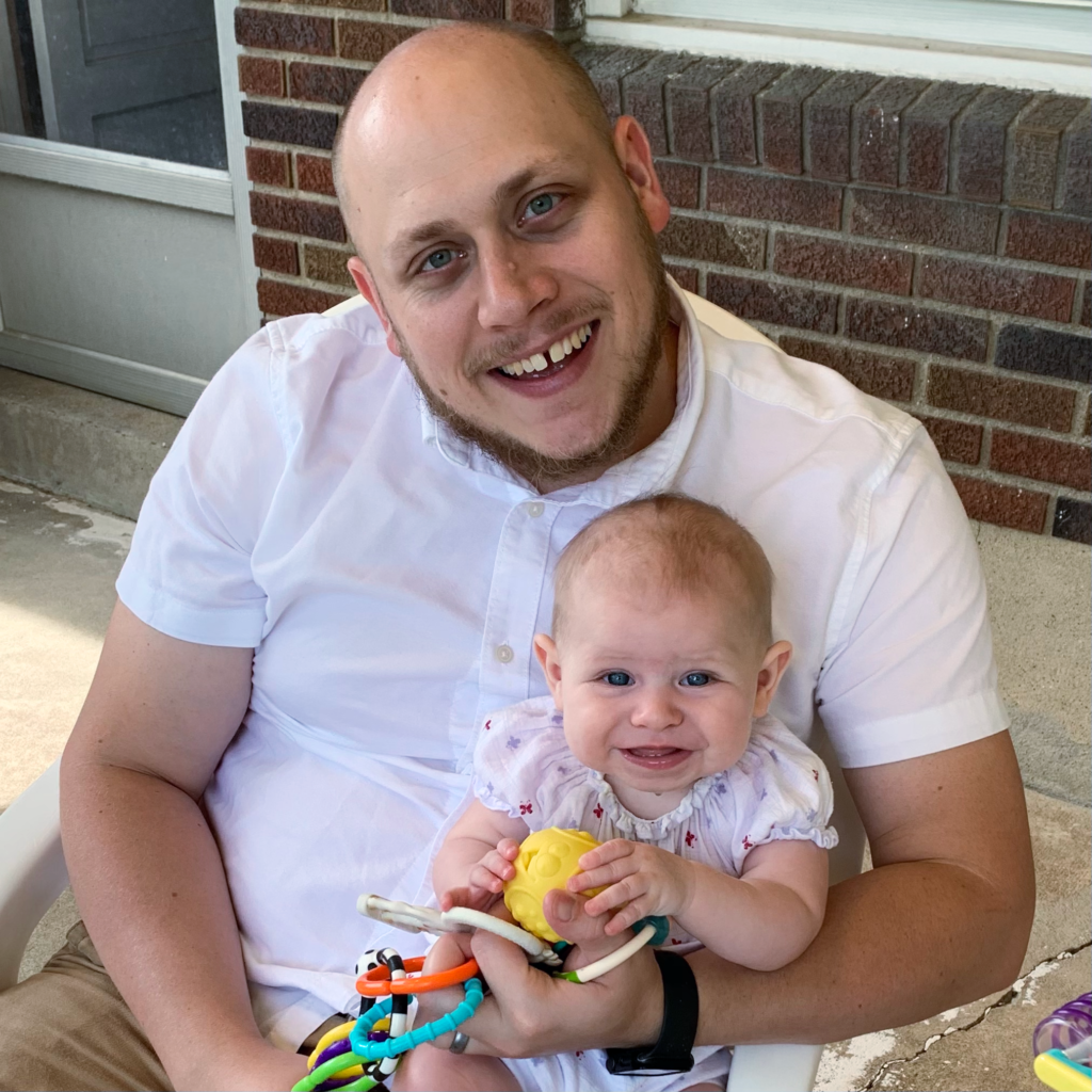 A man is holding a baby in his arms and smiling.