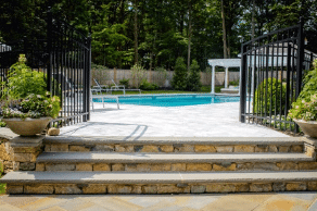 There is a swimming pool in the backyard with stairs leading to it.