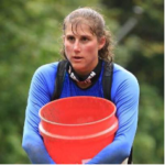 A woman in a blue shirt is holding a red bucket.