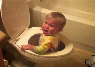A baby is crying while sitting in a toilet
