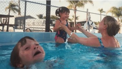 A woman and two children are playing in a swimming pool.