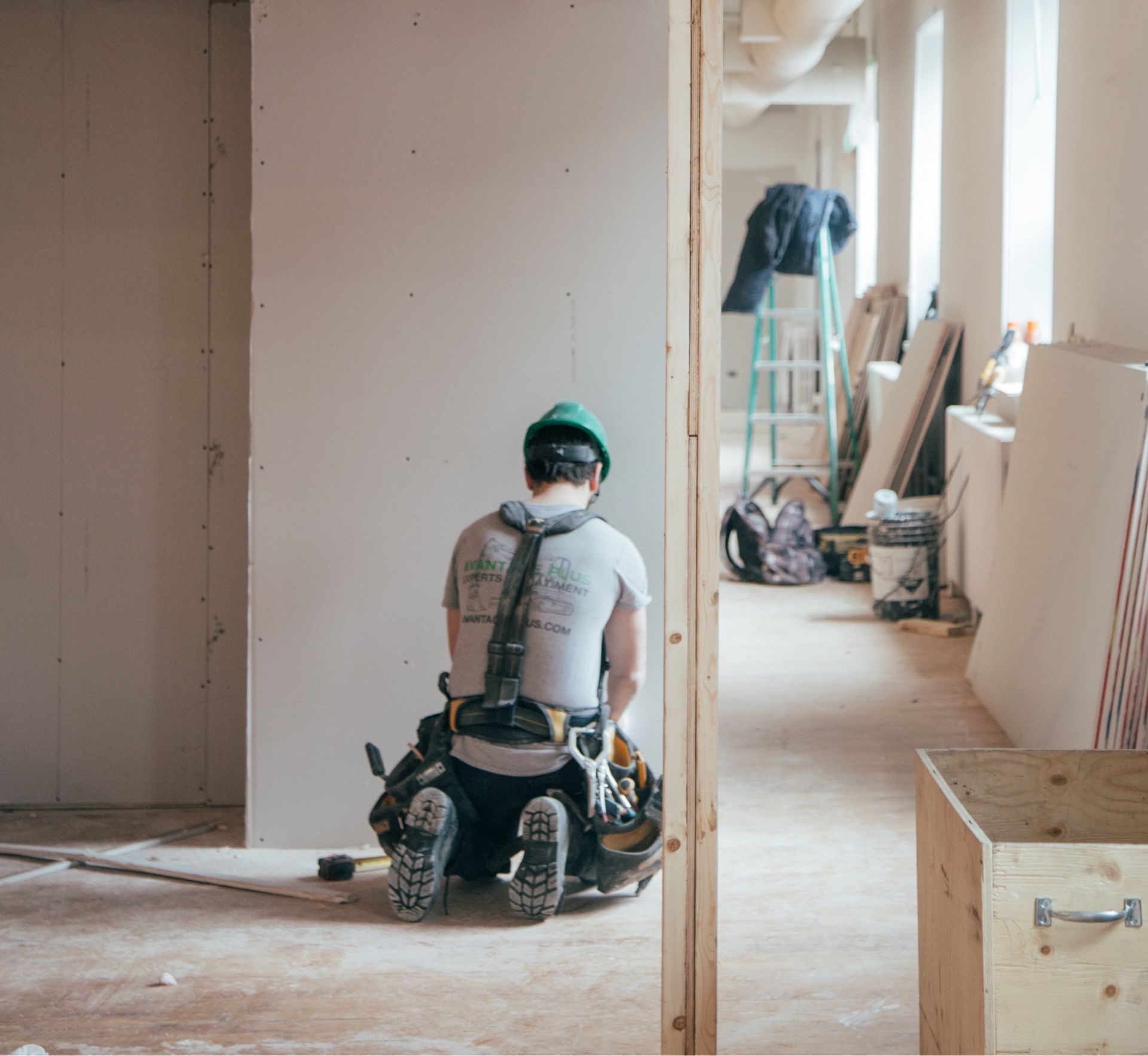 A man is sitting on the floor in a room under construction.