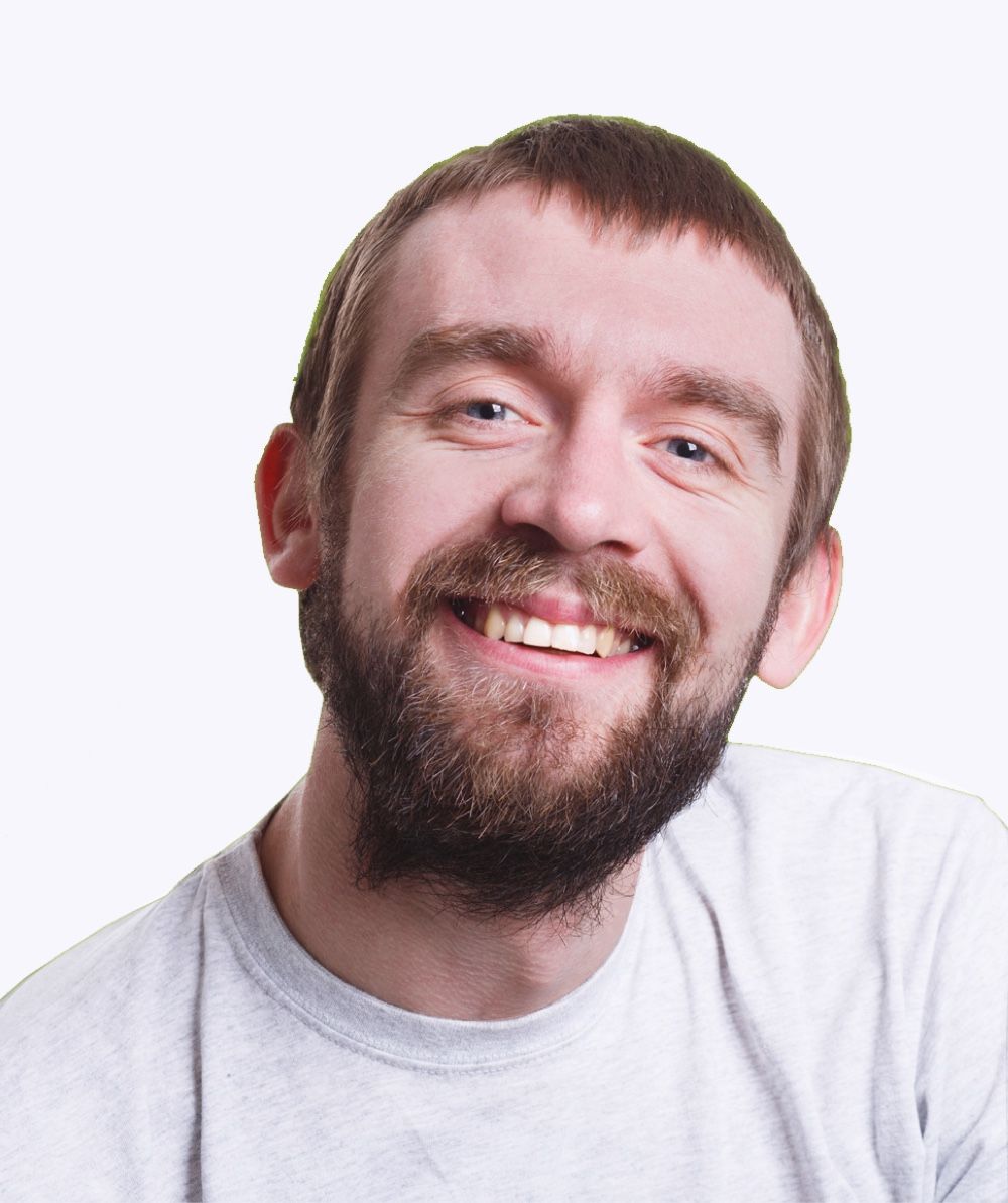 Man with a beard smiling widely, wearing a light gray t-shirt.