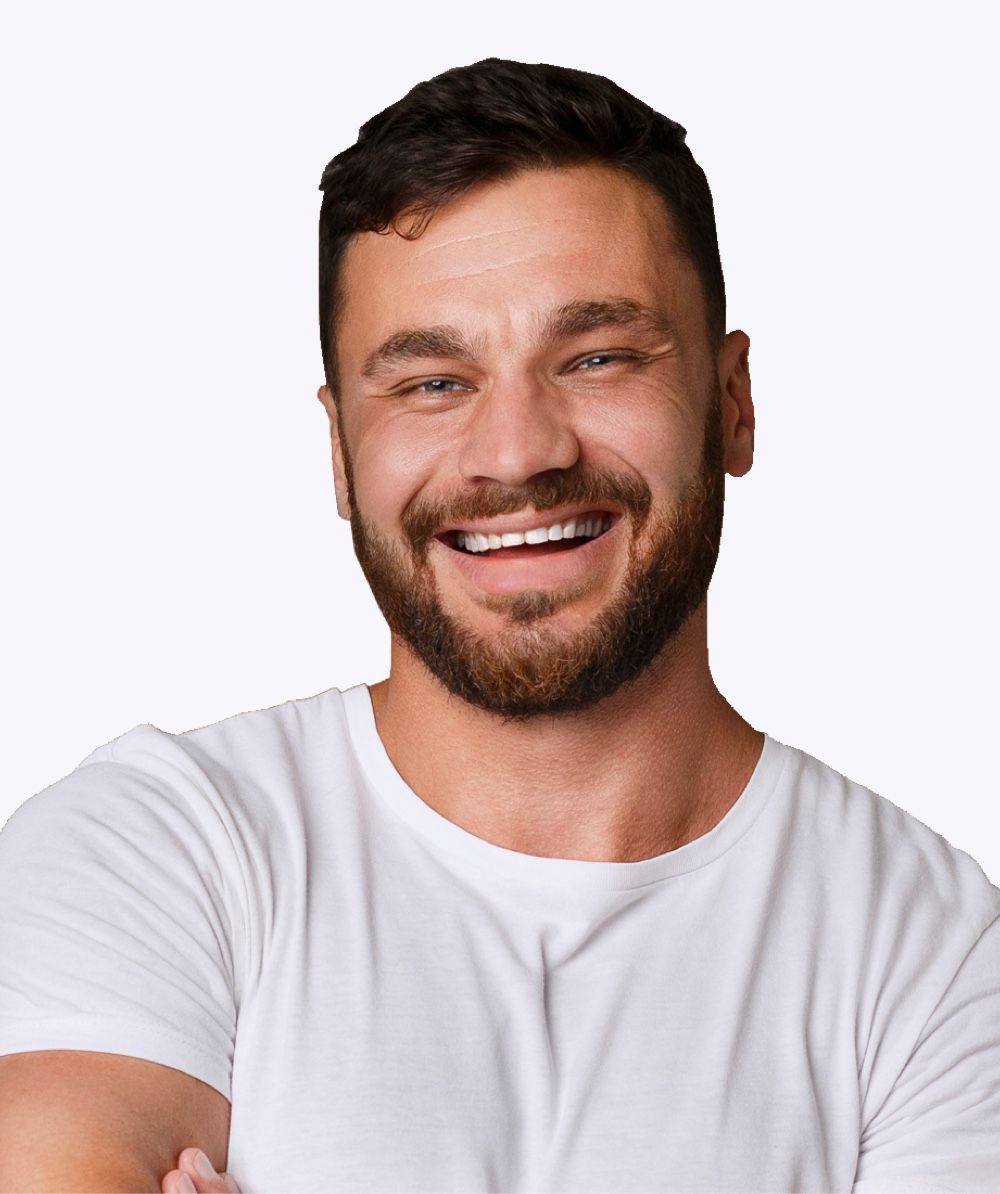 Man with a full beard smiling broadly, wearing a white t-shirt.
