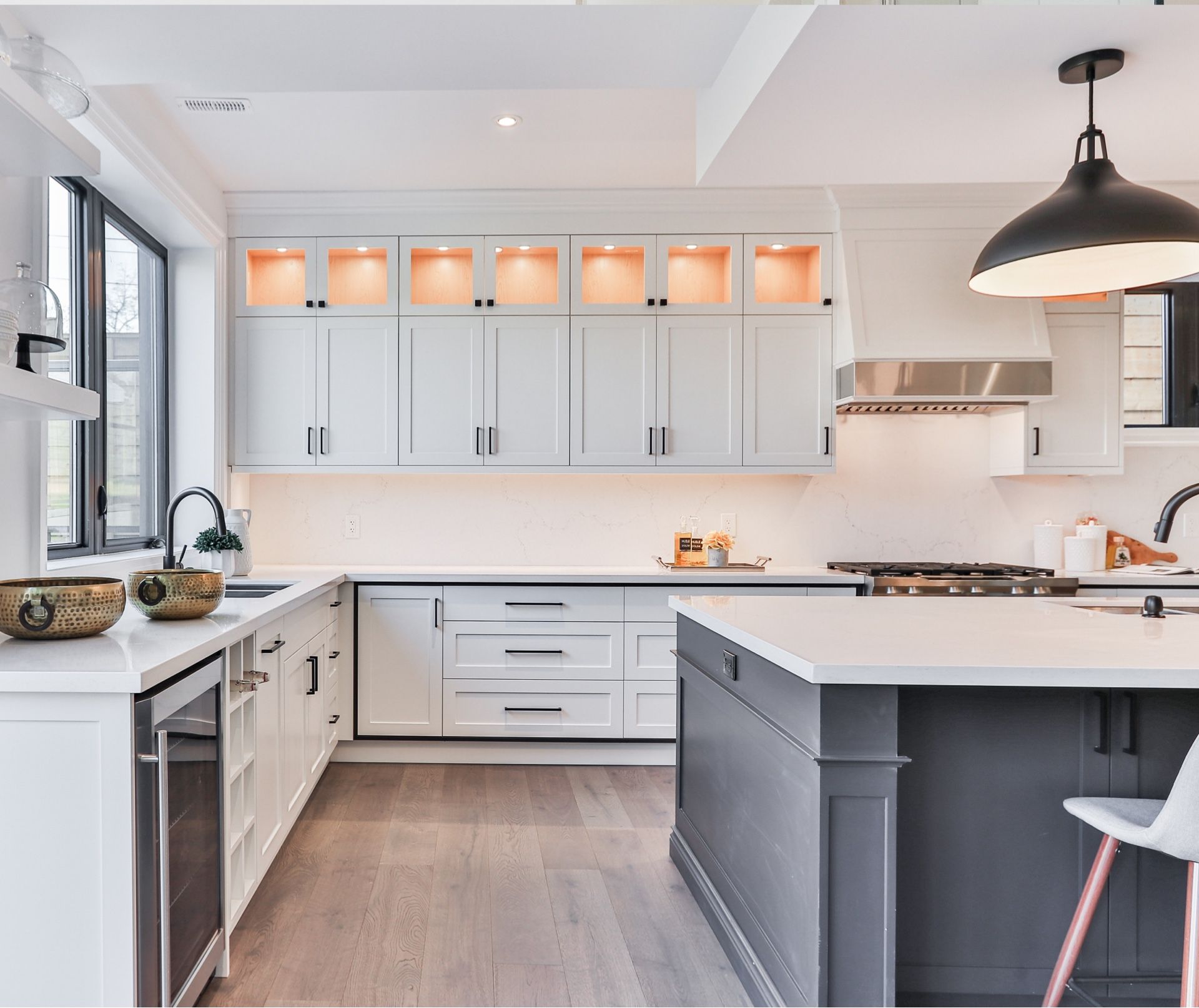 Modern white kitchen with gray island, light wood floors, and black accents.