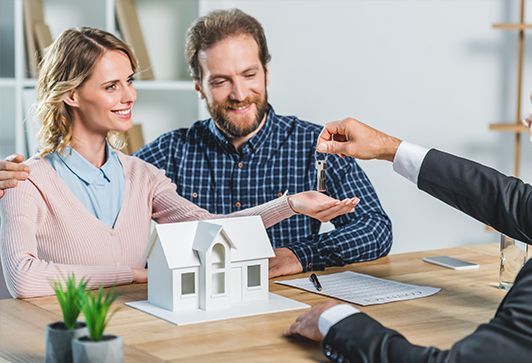 Couple reviewing a house model with a real estate agent at a table