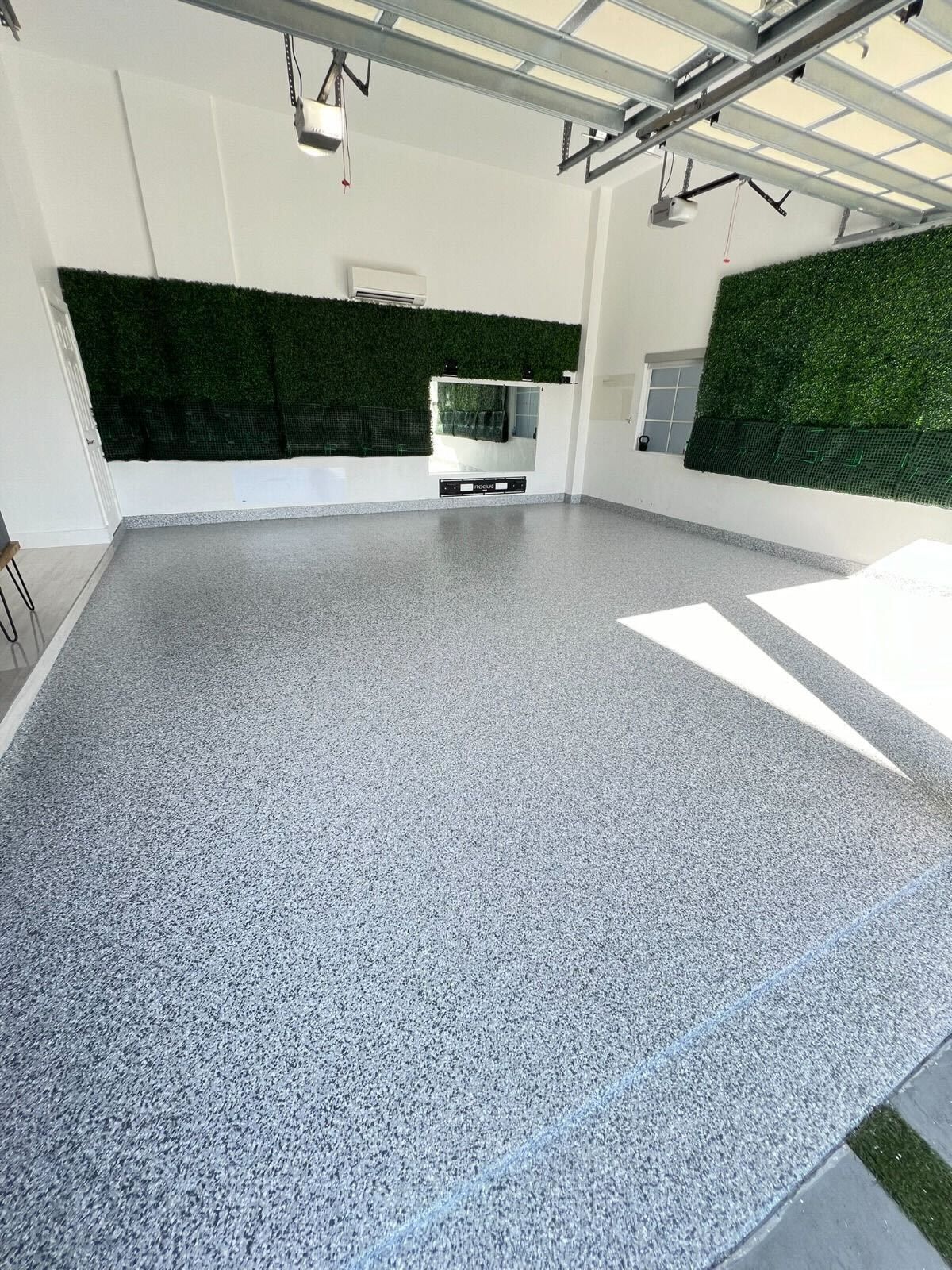 Empty modern room with speckled floor, white walls, and large green wall panels.