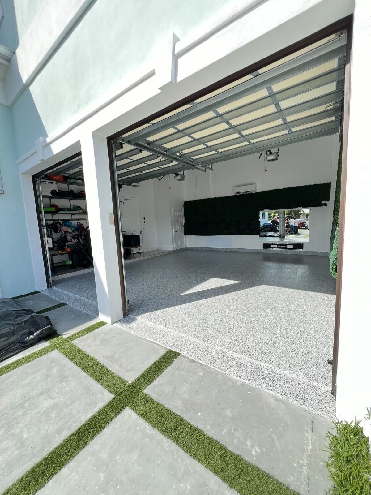 Open garage with speckled floor, white walls, and metal roof in a modern home exterior