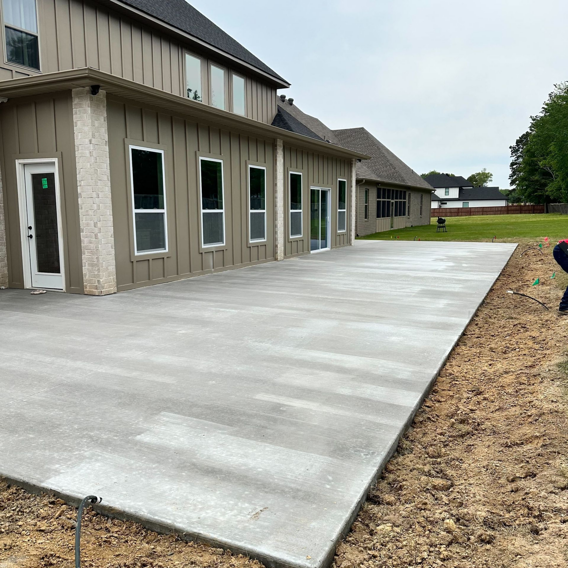 Concrete walkway beside a beige building with multiple windows and doors, leading to an open grassy area.