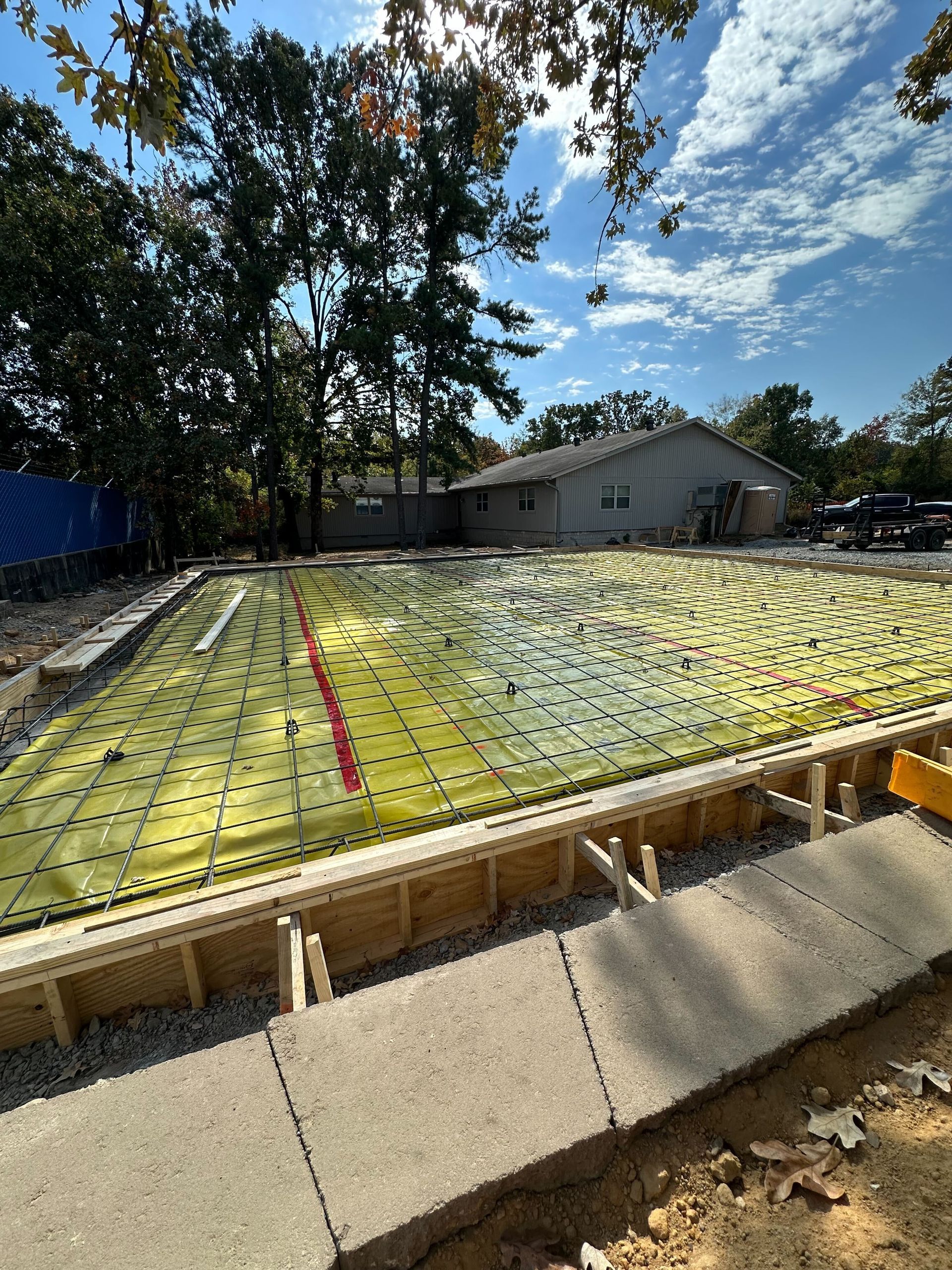 A concrete foundation is being built in a backyard with a house in the background.