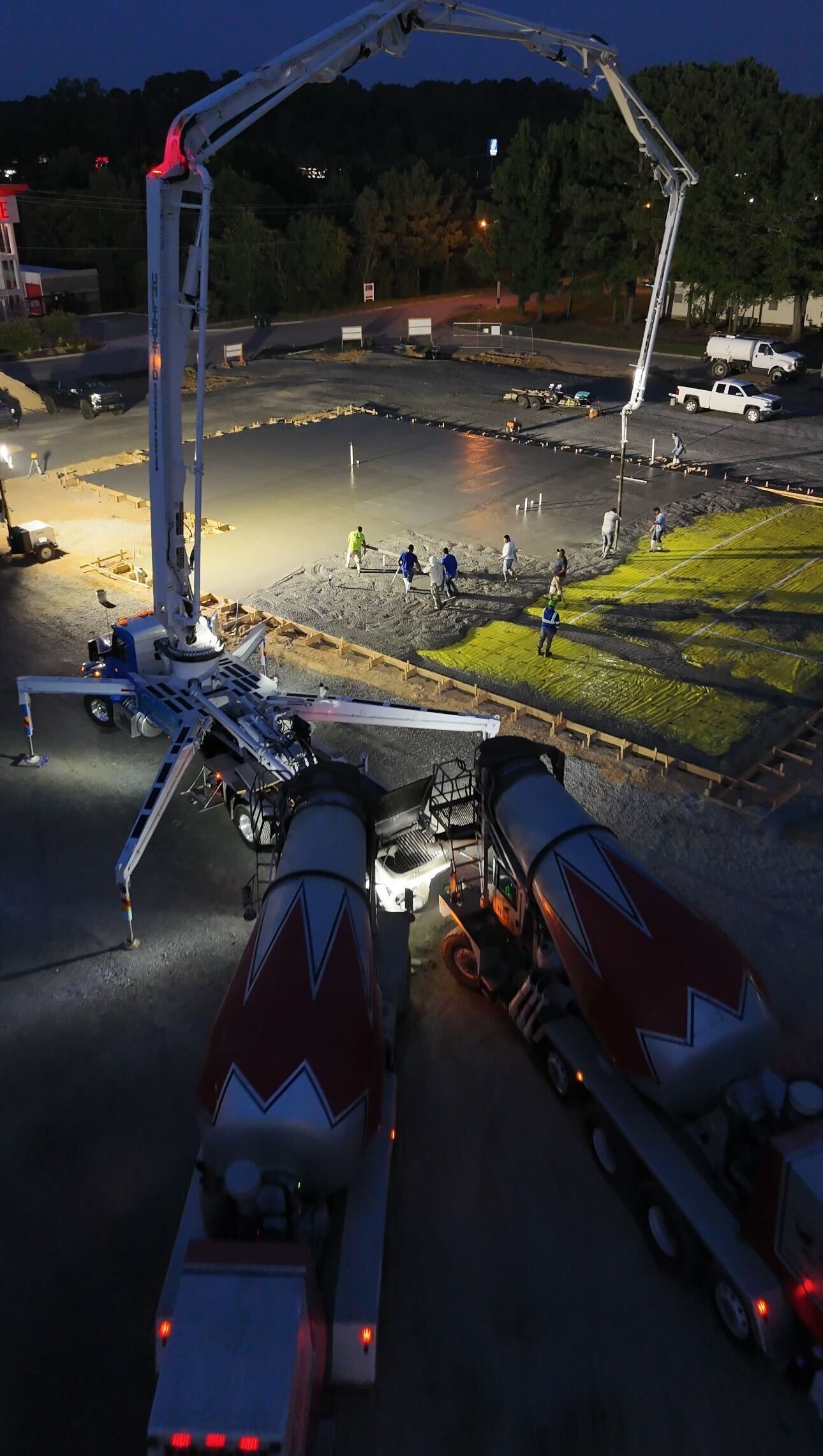 Concrete pouring at a construction site at night, with a large boom pump and workers nearby.