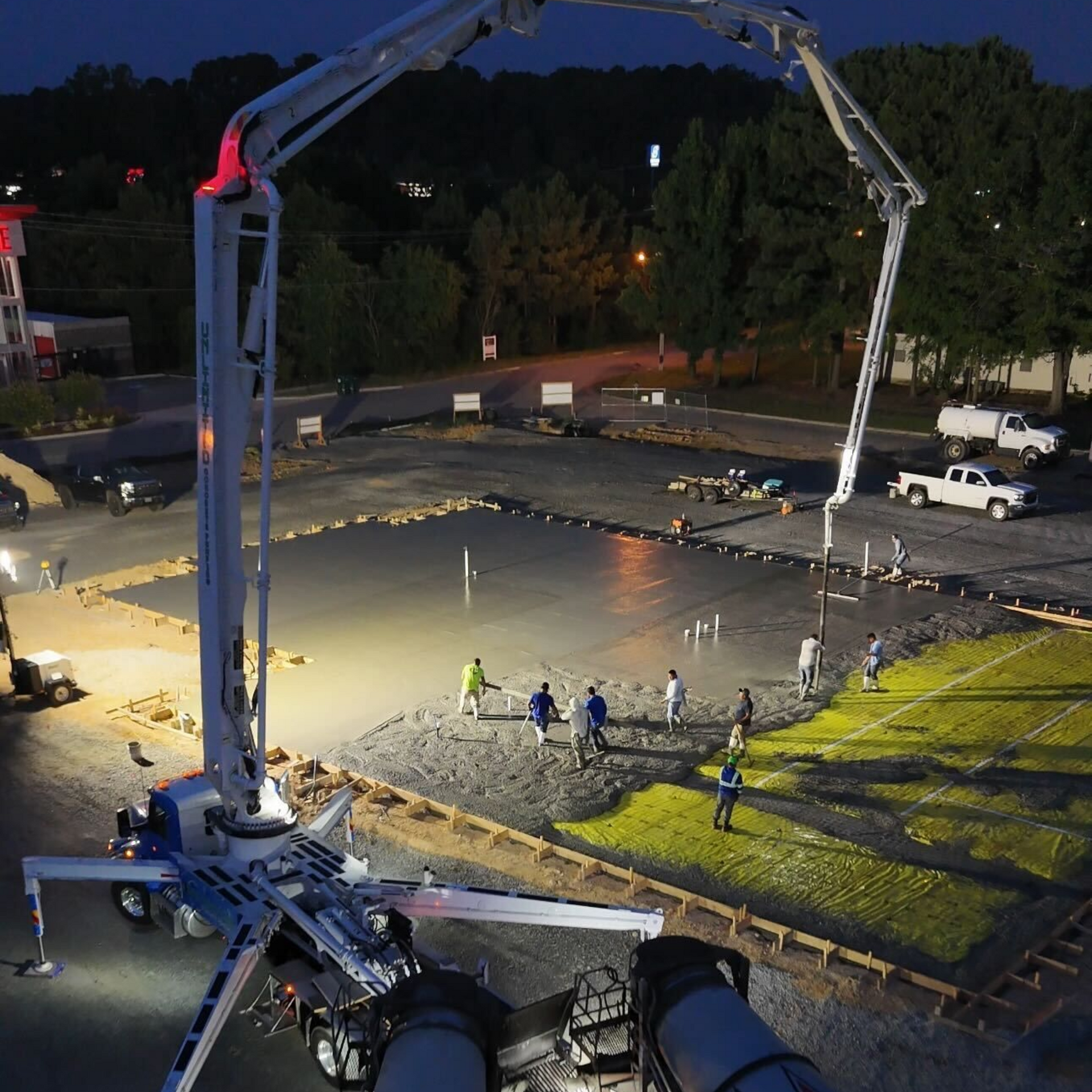 Concrete being poured at night by a large boom pump on a construction site