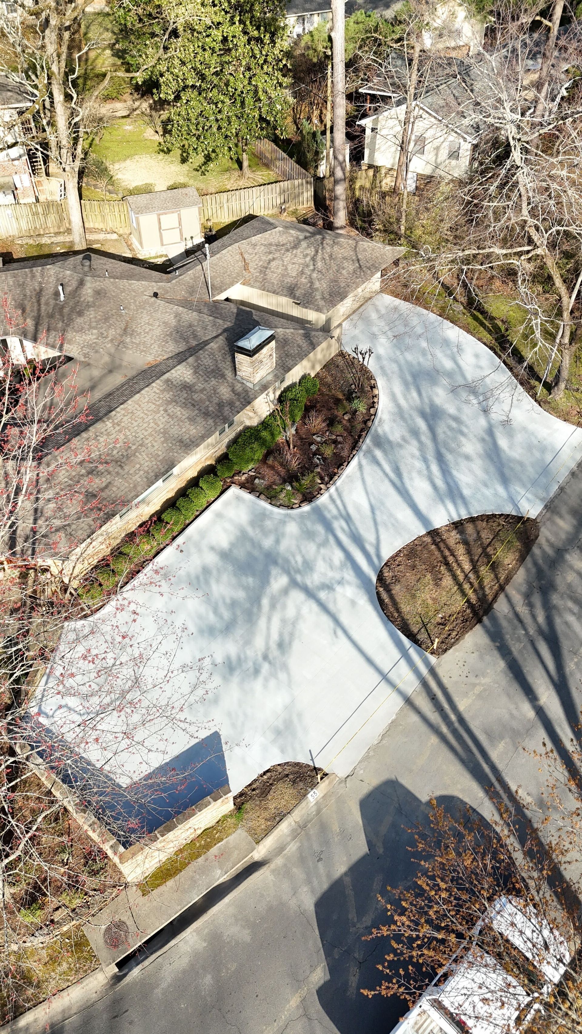 Curved light-blue skatepark bowl beside trees and a paved path, viewed from above.