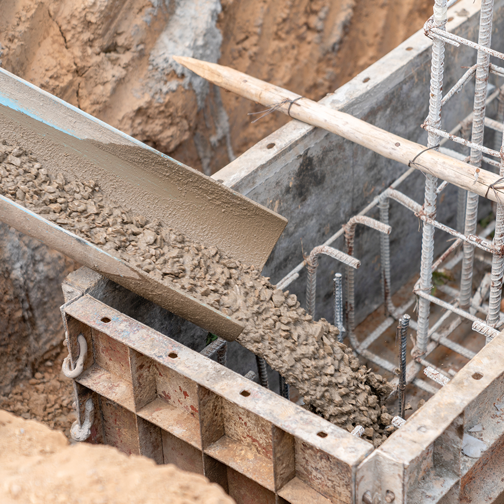 Concrete is being poured into a concrete form at a construction site.