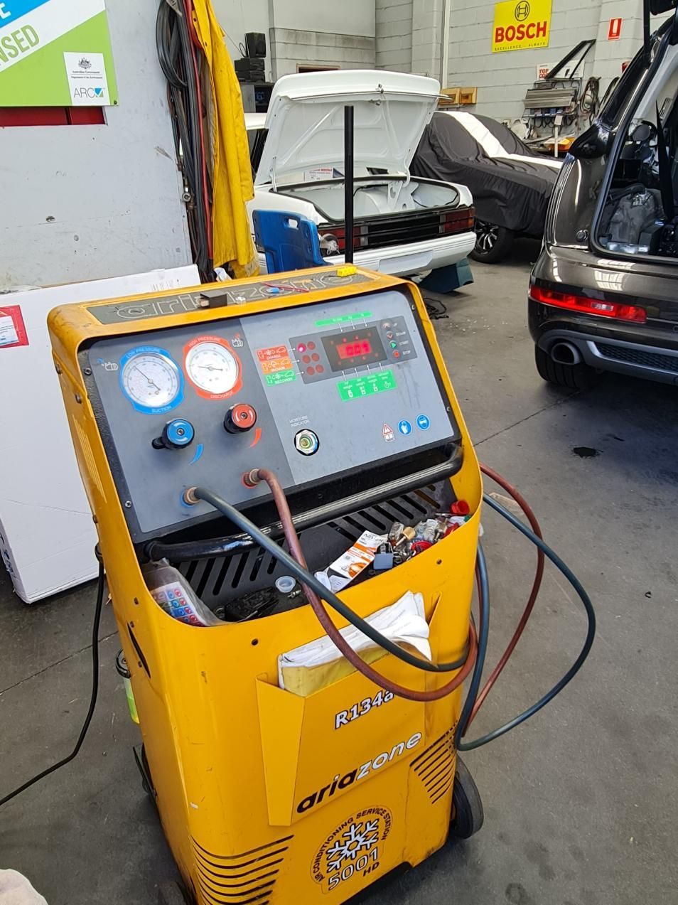 A Yellow Air Conditioning Machine is in a Garage Next to a Car — Regional Auto Electrics In Fairy Meadow, NSW