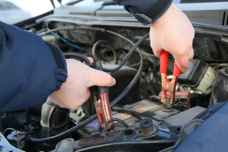 A Person is Charging a Car Battery With Jumper Cables — Regional Auto Electrics In Fairy Meadow, NSW