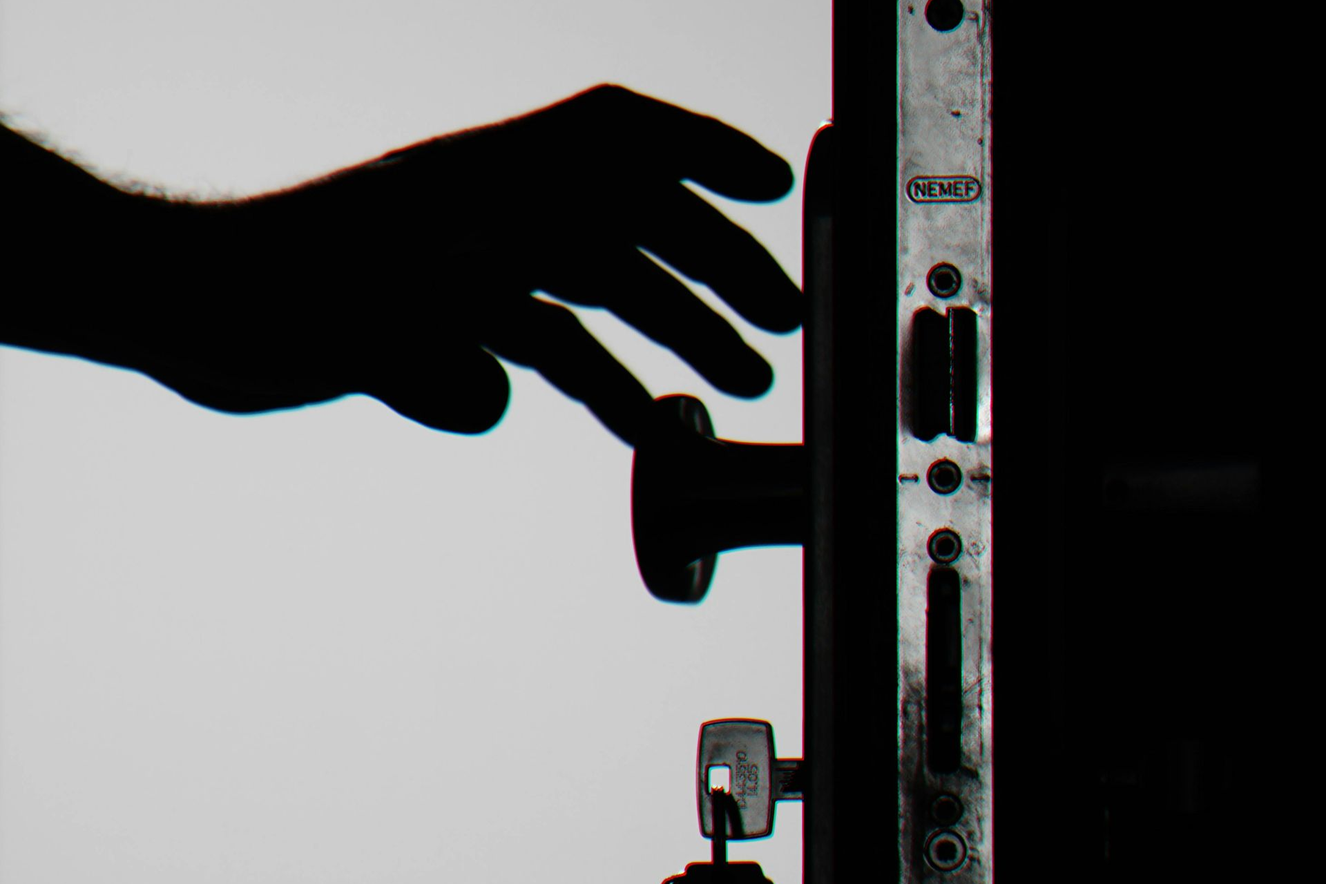 Silhouette of hand reaching for doorknob. Dark against white, implying a locked door.