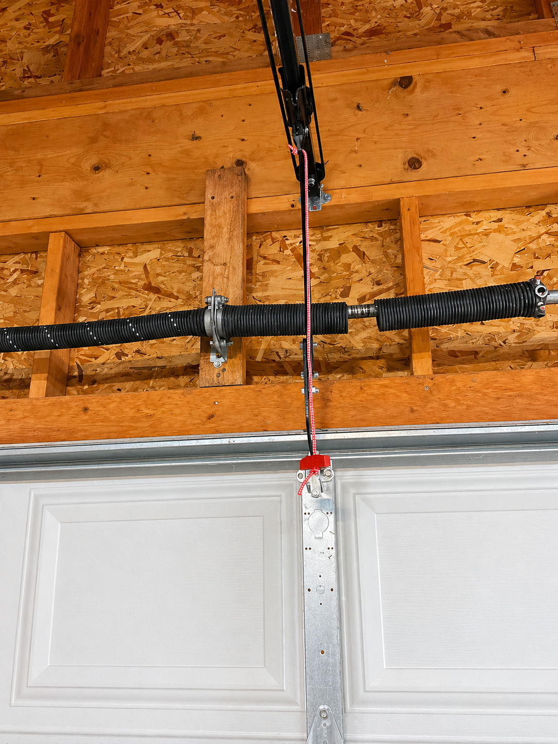 Garage wall with mounted garage door opener hardware, tracks, and a car roof in the foreground Garage wall with mounted garage door opener hardware, tracks, and a car roof in the foreground