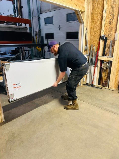Man using a red drill to install a garage door bracket inside an unfinished garage