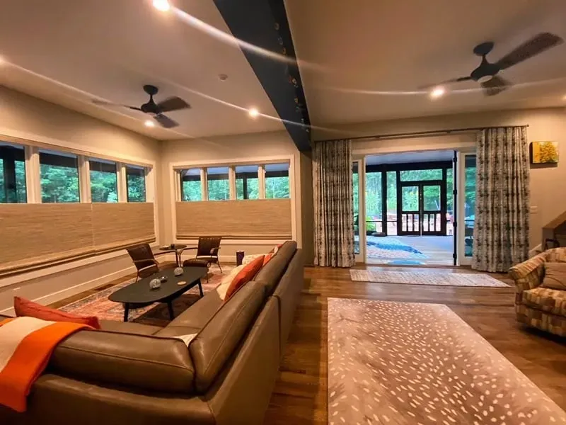 A spacious living room with a leather sectional, hardwood floors, ceiling fans, and sliding doors leading to a patio.