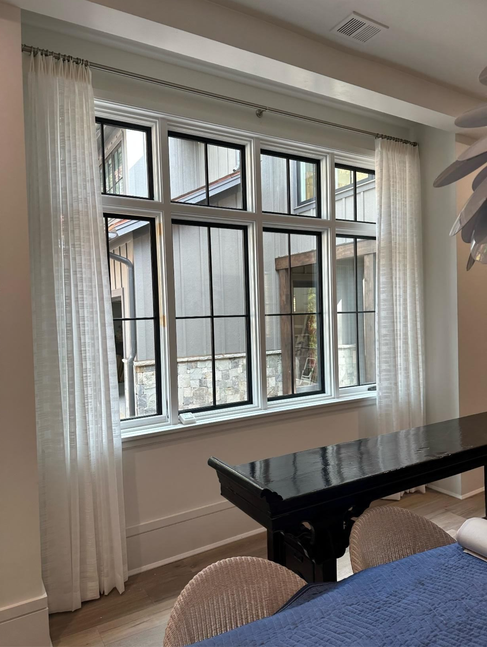 Living room with large window, sheer curtains, and a dark coffee table beside a blue sofa
