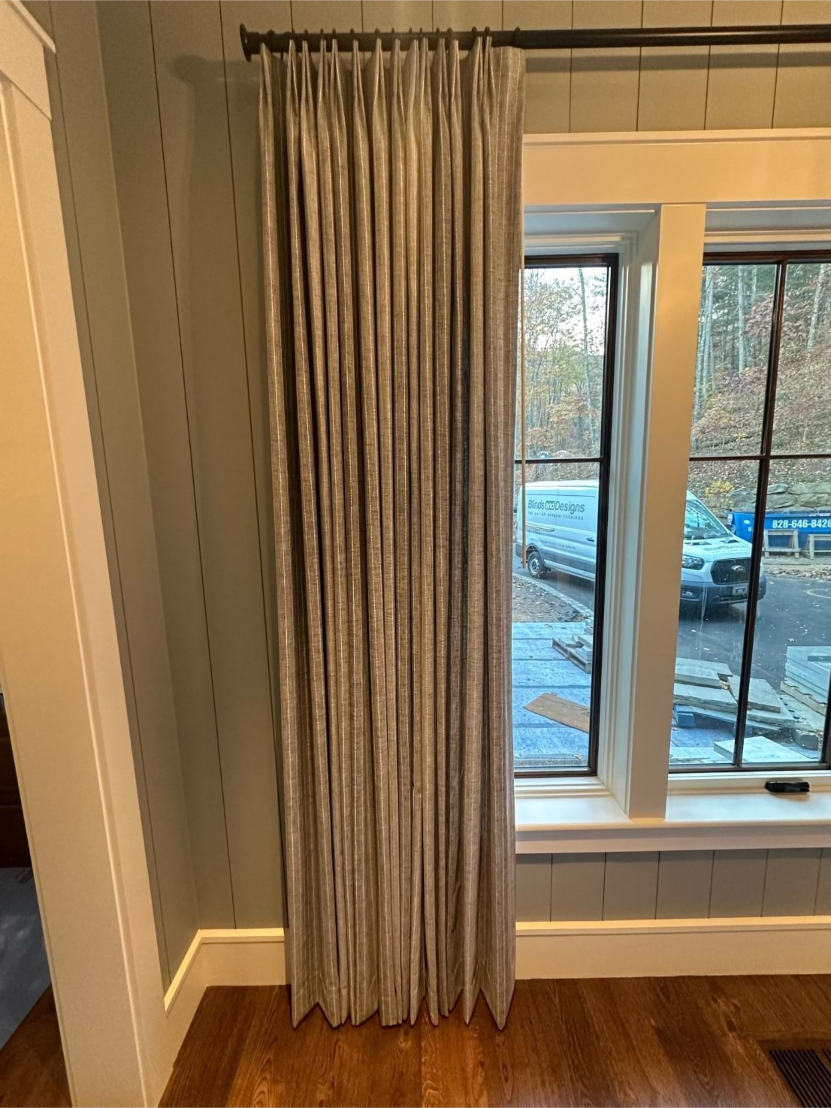 Floor-length beige curtains beside a window with a snowy outdoor view and white radiator below.