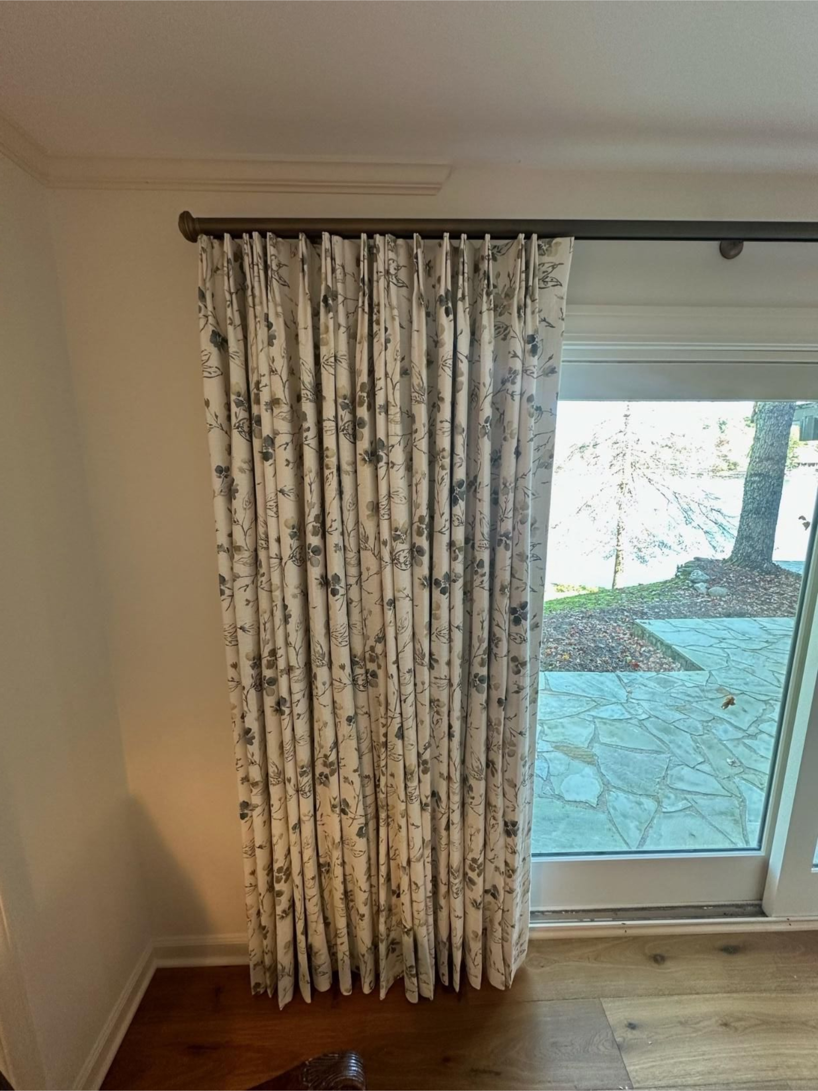Curtained sliding glass door beside a hardwood floor in a sparsely furnished room