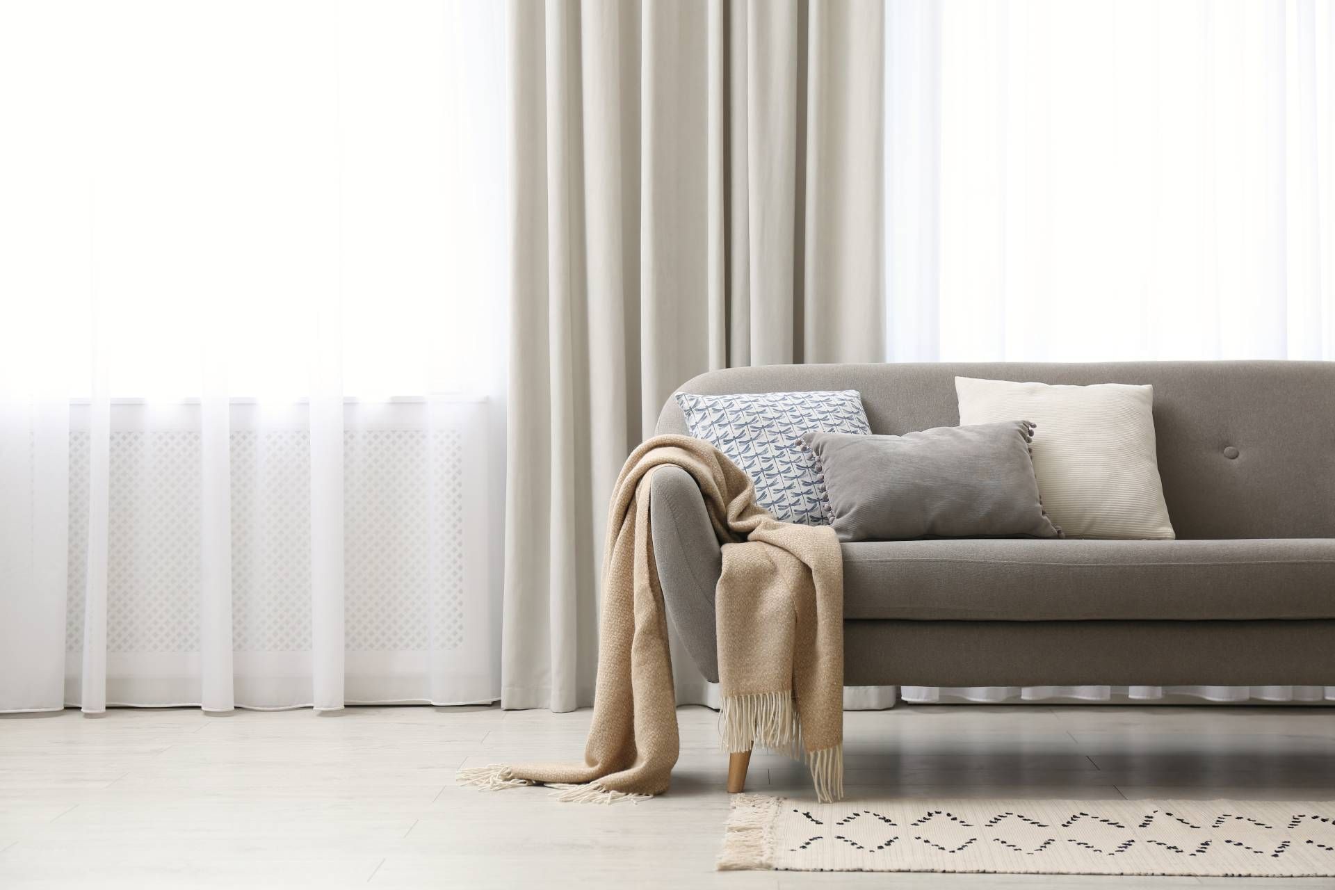 Floor length white and beige drapery behind a modern sofa near Fletcher, NC