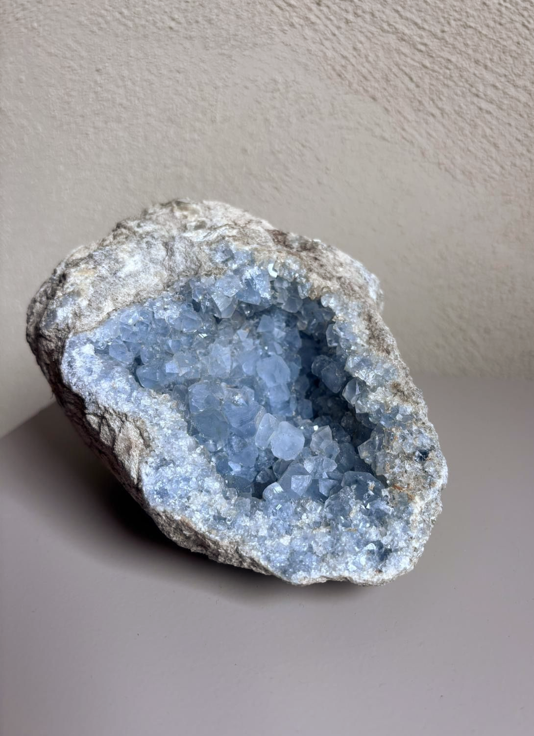 Grote celestien geode met fonkelende blauwe kristallen op een tafelblad.