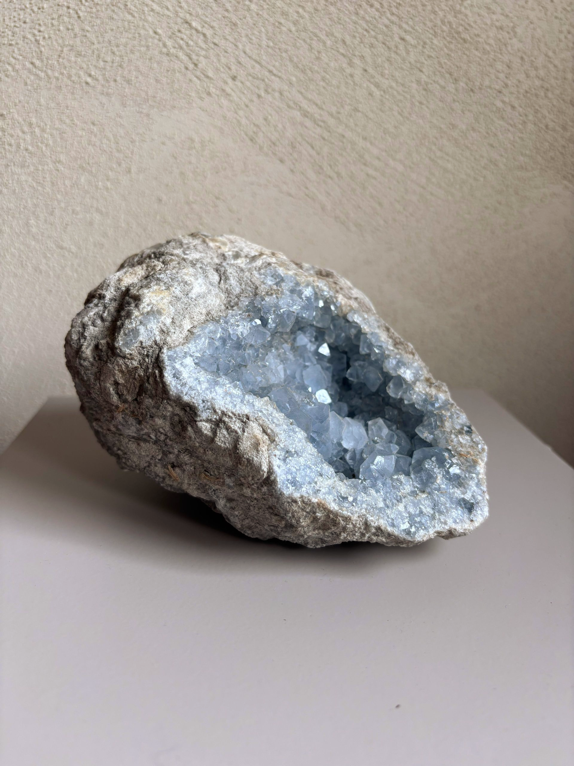 Grote celestien geode met fonkelende blauwe kristallen op een tafelblad.