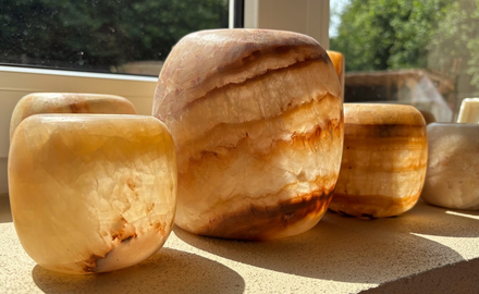Diverse beige en bruin gestreepte alabasters op een vensterbank in het warme zonlicht.