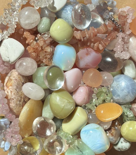 Diverse gepolijste edelstenen en kristallen in pastelkleuren, dicht op elkaar gerangschikt in een close-up.