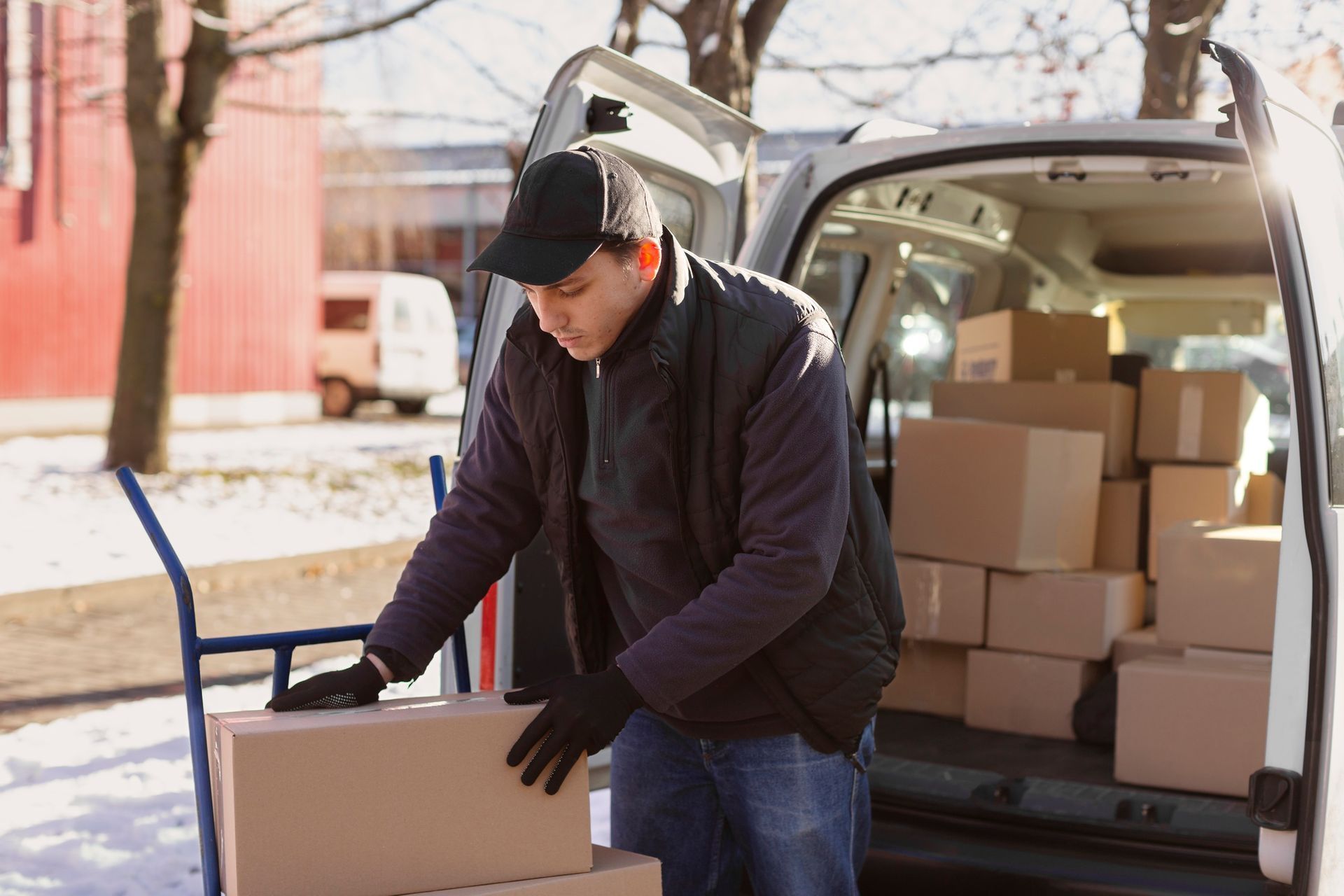 Worker loading cardboard boxes into a delivery van outdoors