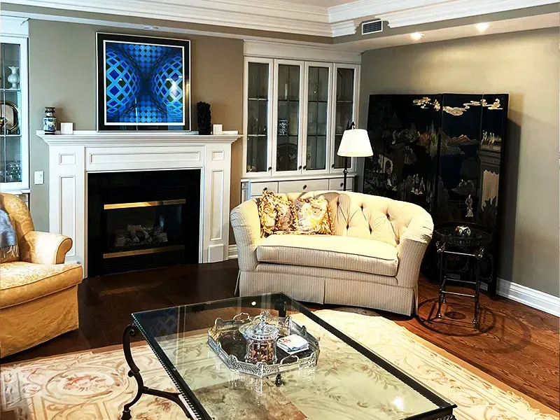 Elegant living room with fireplace, cream sofa, glass coffee table, and hardwood floors