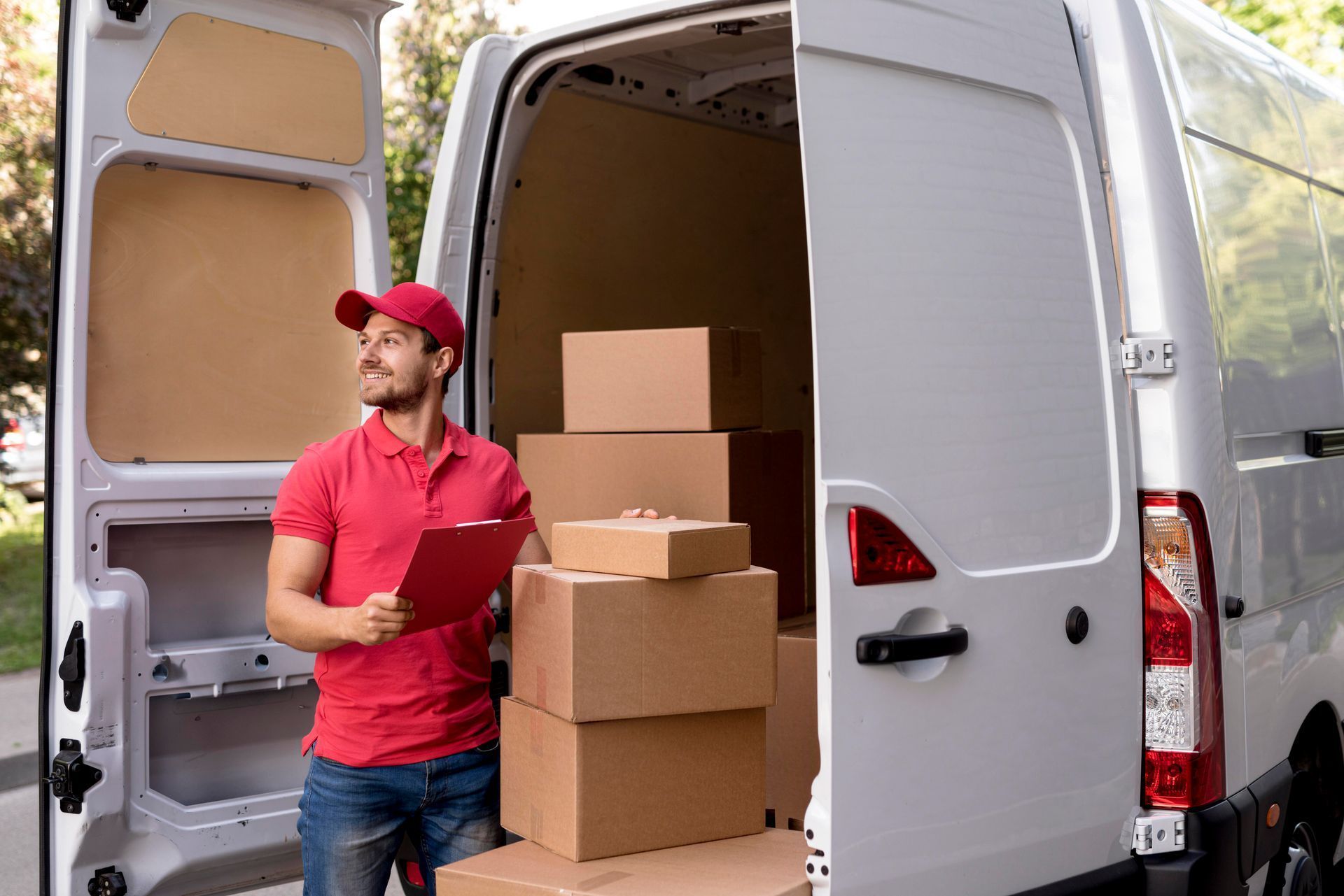 Delivery worker loading cardboard boxes into an open white van
