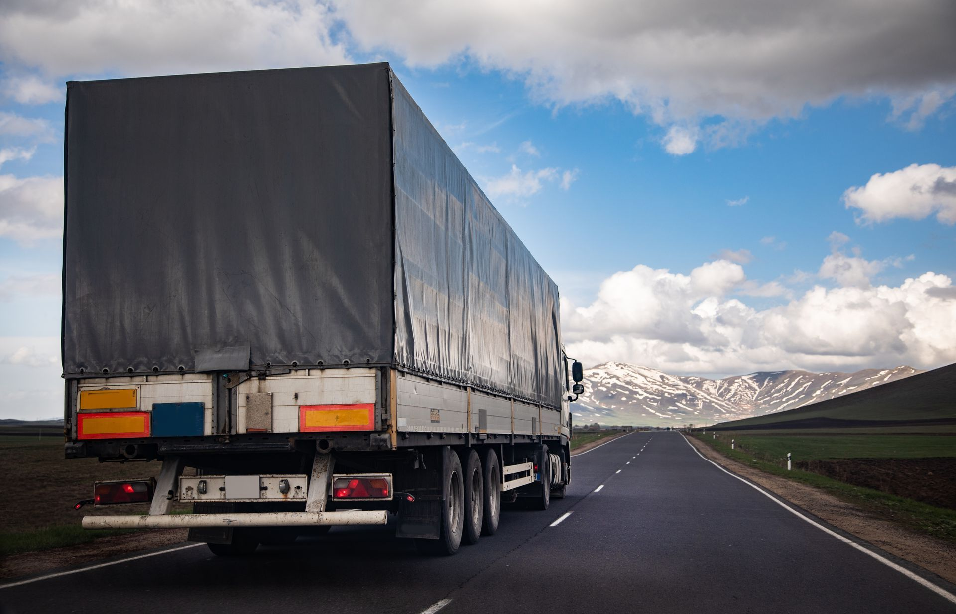 Cargo truck driving on an open highway under a cloudy sky