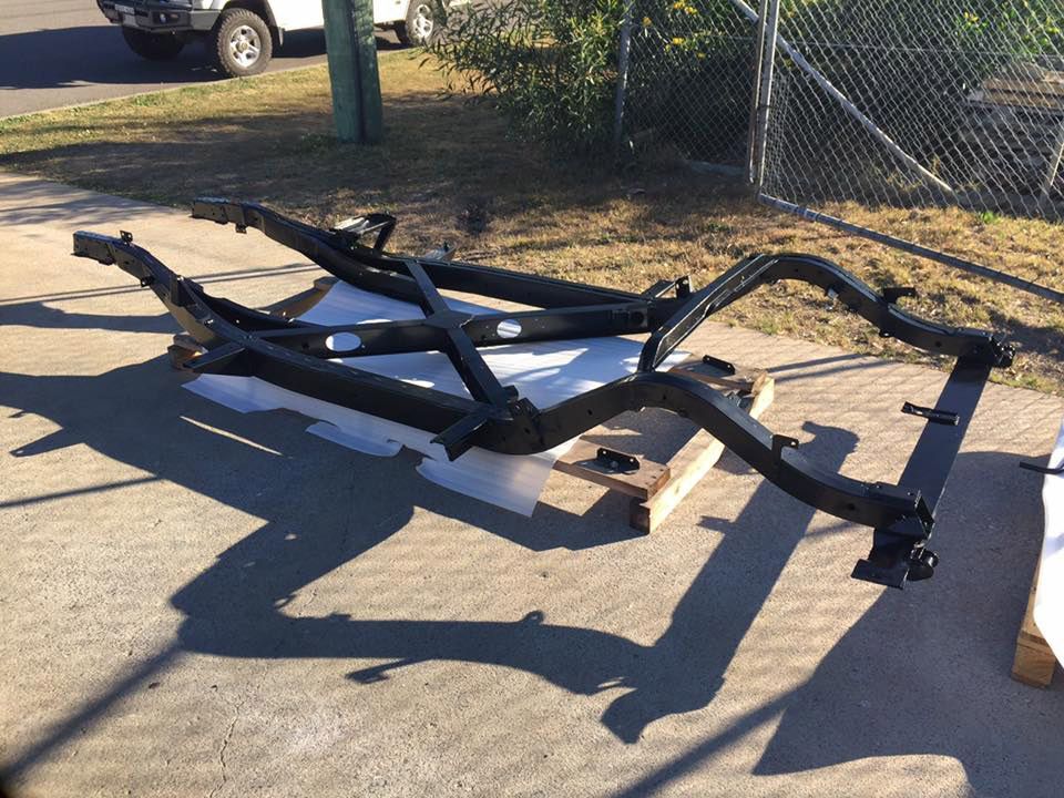 A Car Frame Is Sitting On The Ground In Front Of A Chain Link Fence — Hunter Powder & Paints In Maitland, NSW
