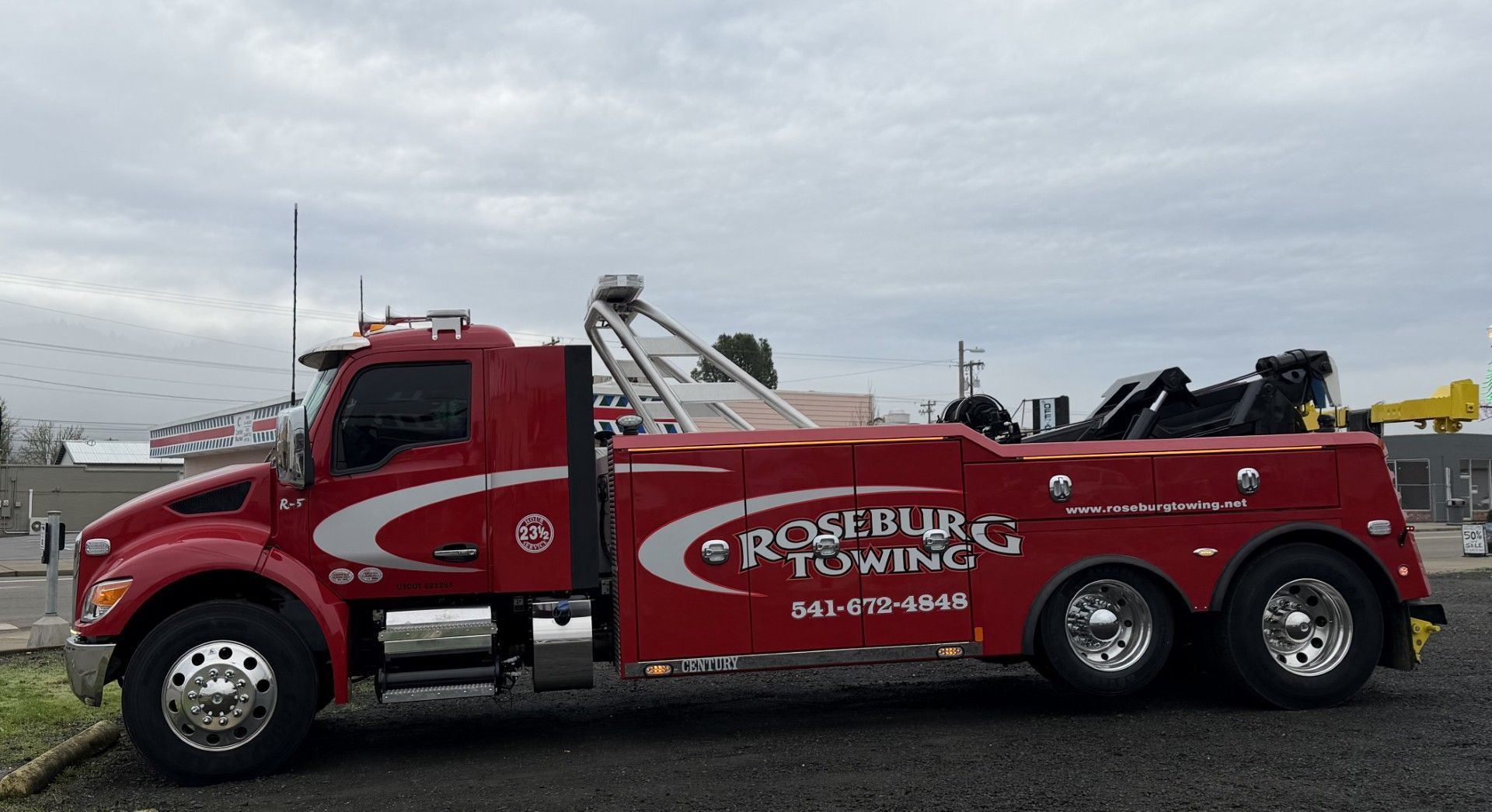 Red Roseburg Towing truck with logo parked outdoors.
