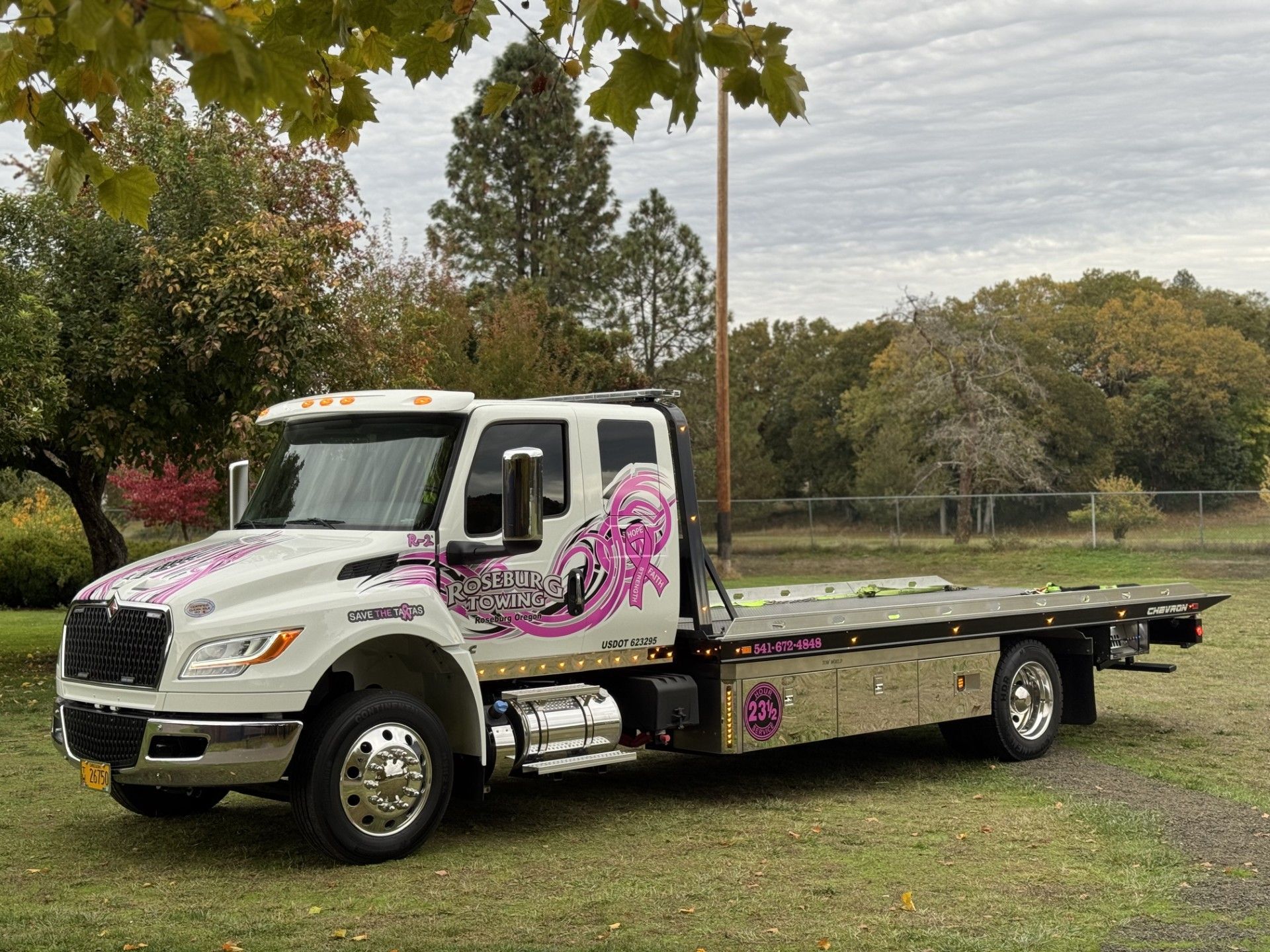 White tow truck with pink octopus graphics parked outdoors.