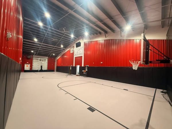 An empty basketball court in a gym with red walls