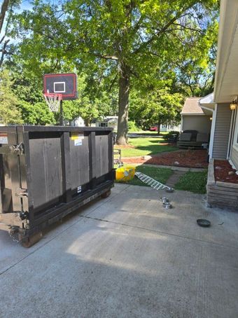 A man is loading a dumpster into a dump truck.