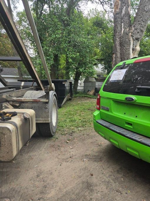 A dumpster truck is parked next to a dumpster.