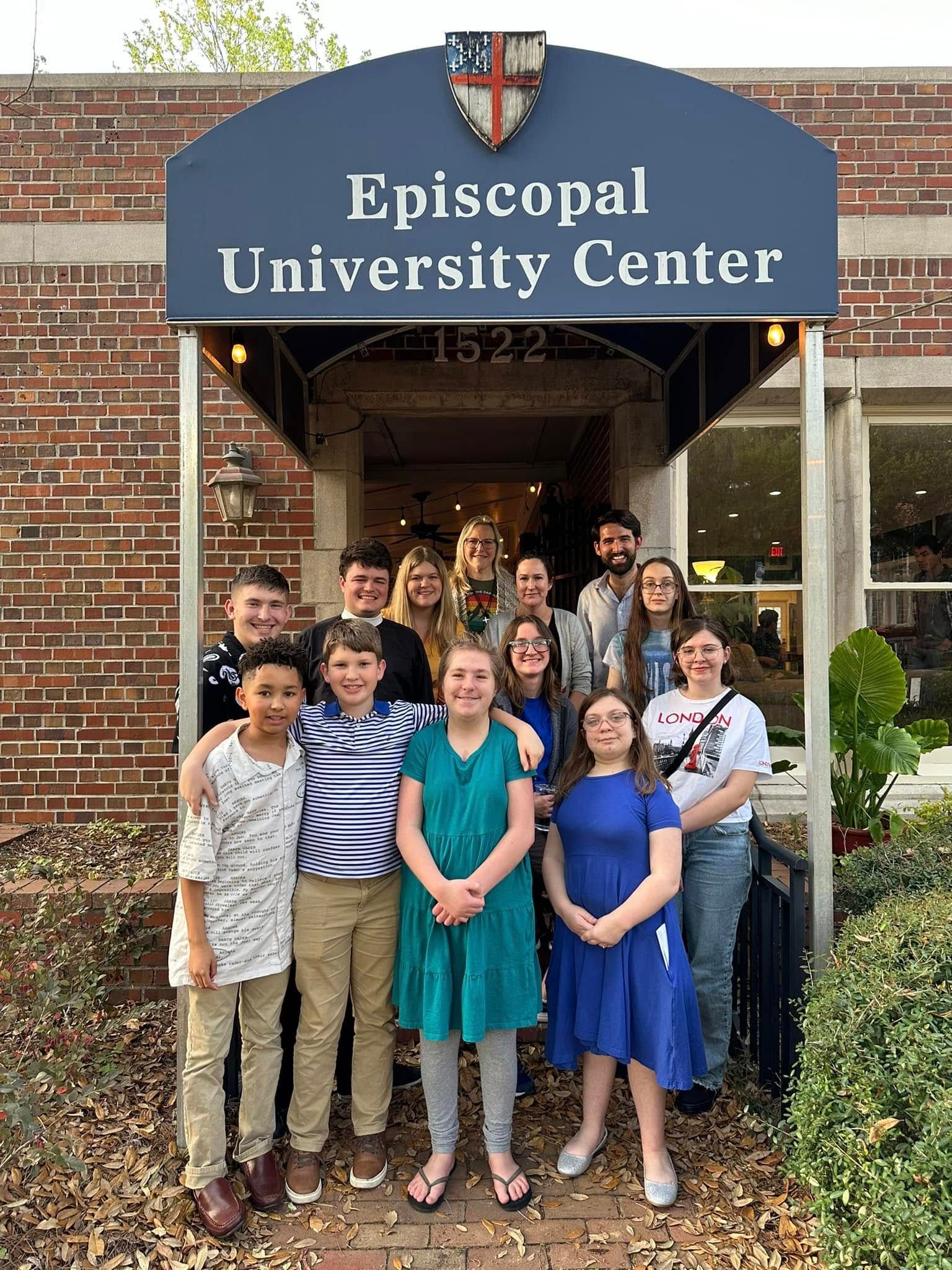 A group of church members standing under a blue awning that says