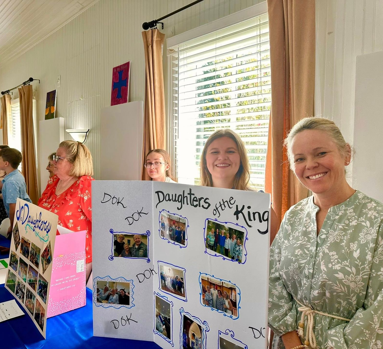 Daughters of the King trifold poster with members smiling behind at the Ministry Fair