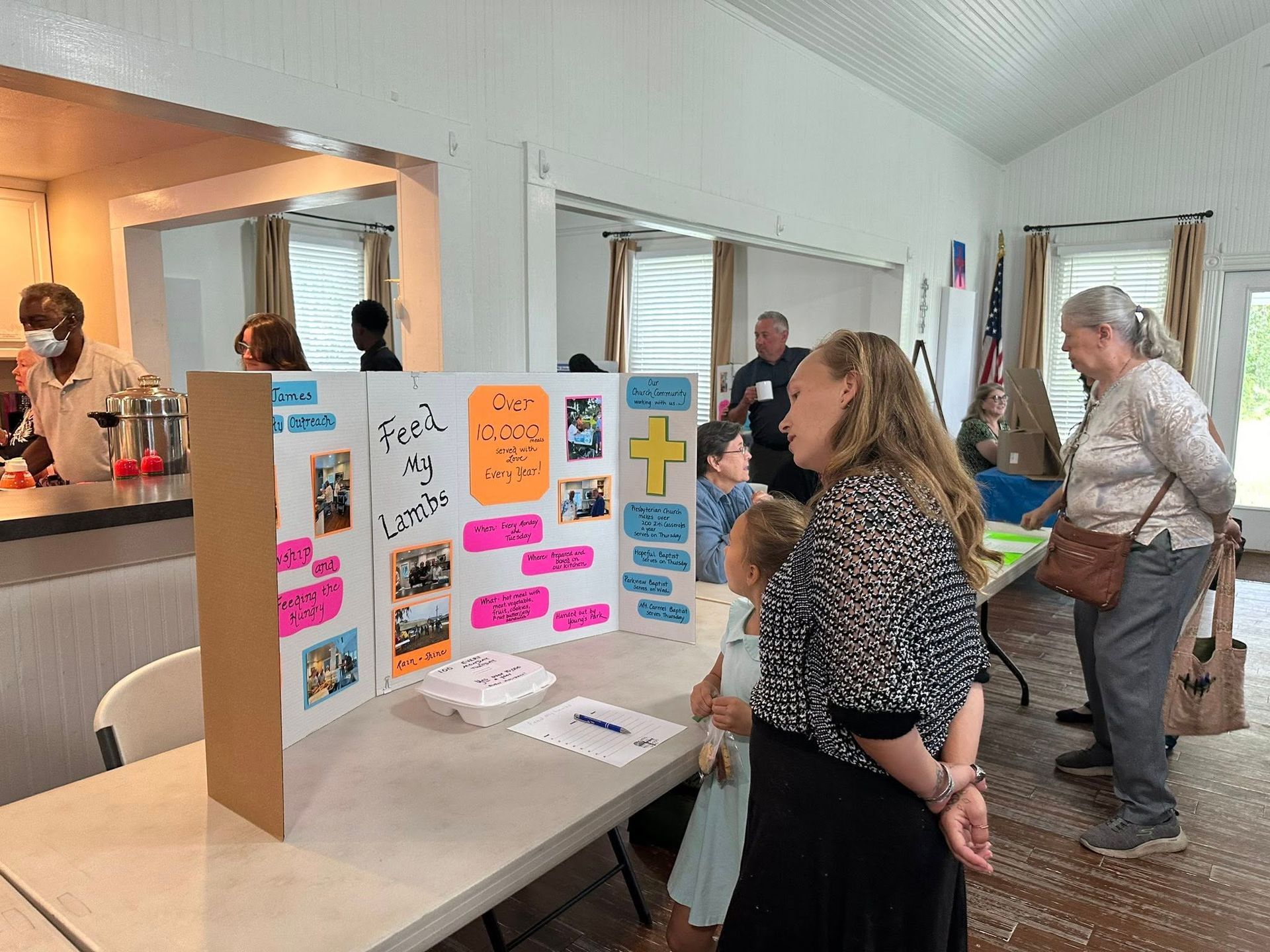 Church members browse various trifold poster boards on tabletops inside Parish Hall during the Ministry Fair